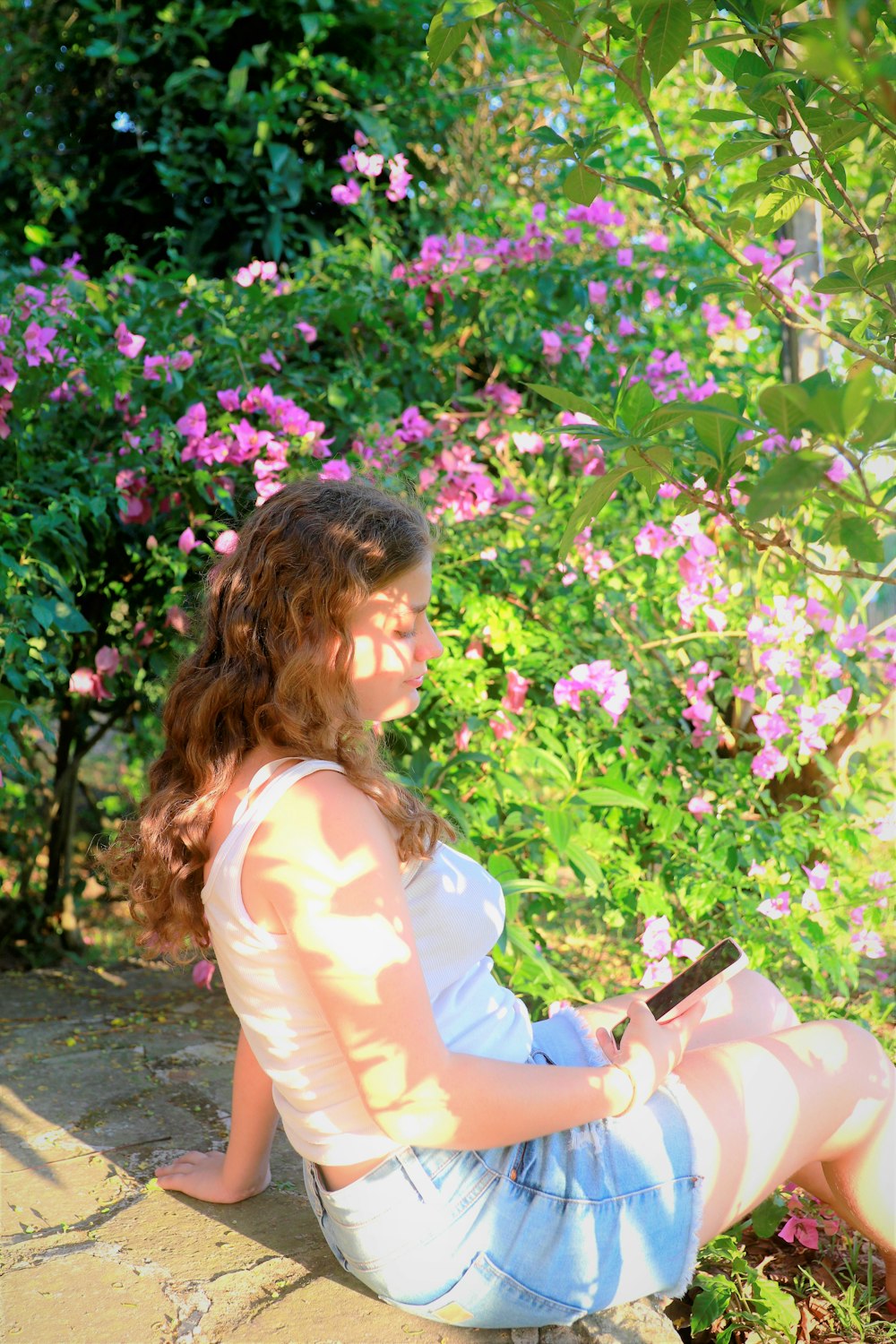 a woman sitting on the ground in front of flowers