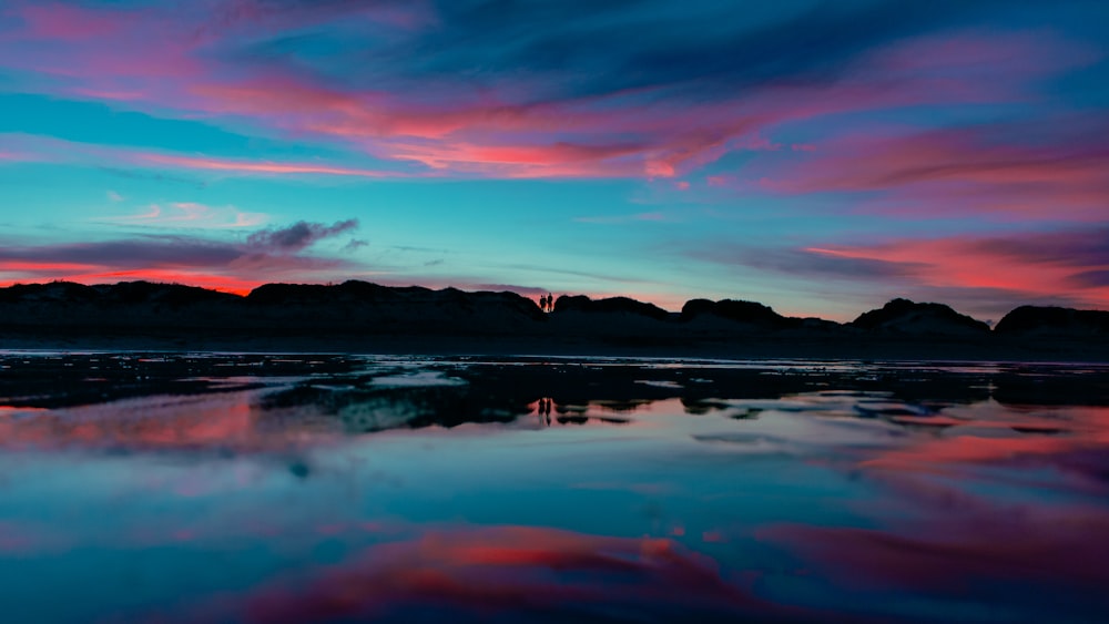 a colorful sky is reflected in a body of water