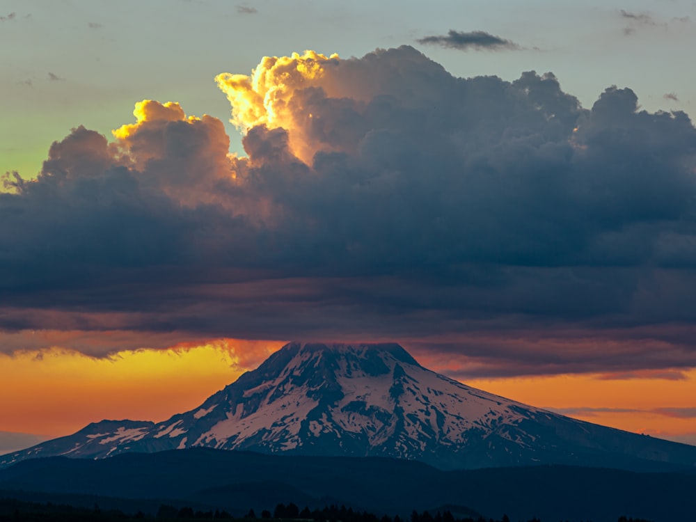 a mountain covered in clouds at sunset