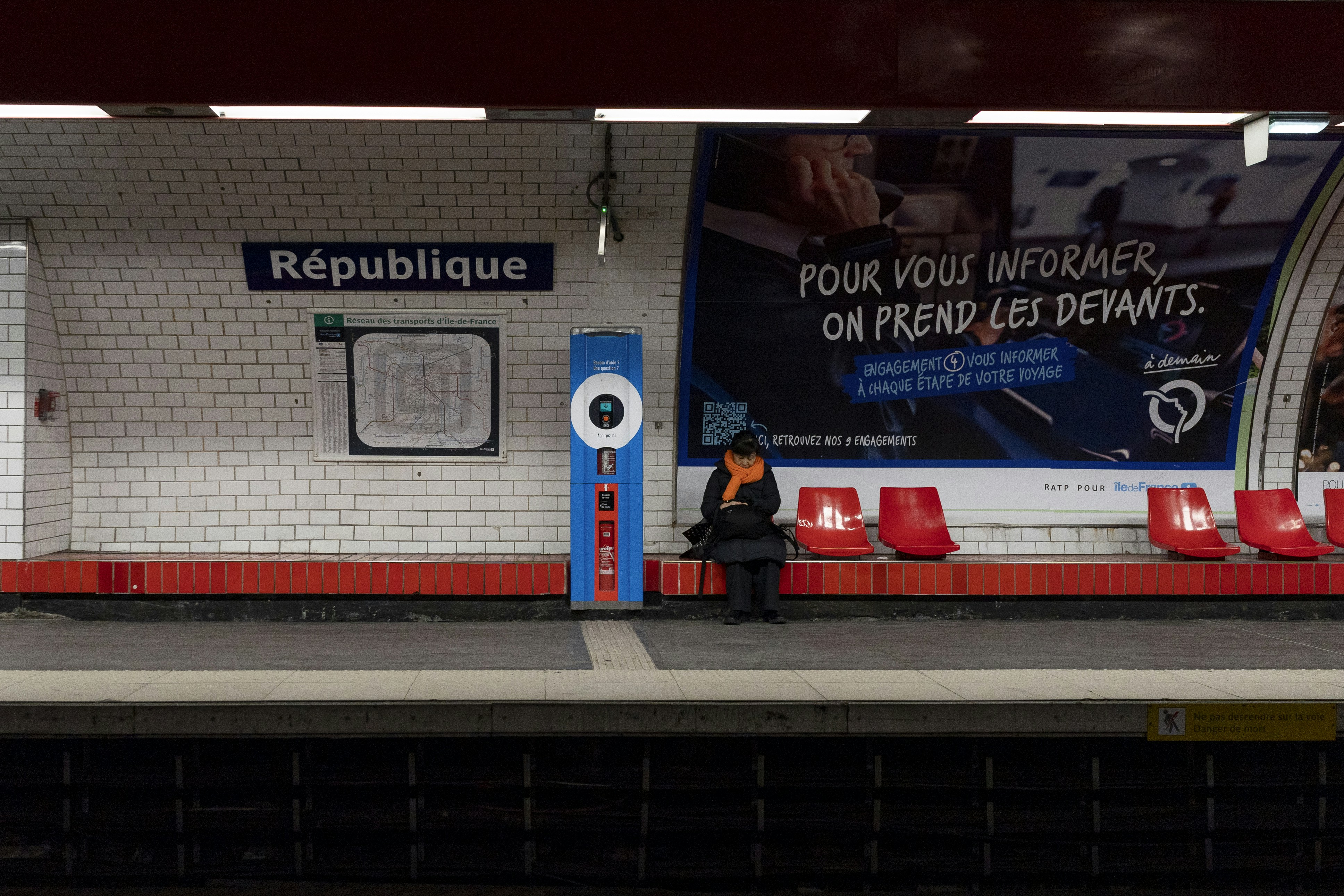 a person sitting on a bench in front of a train station