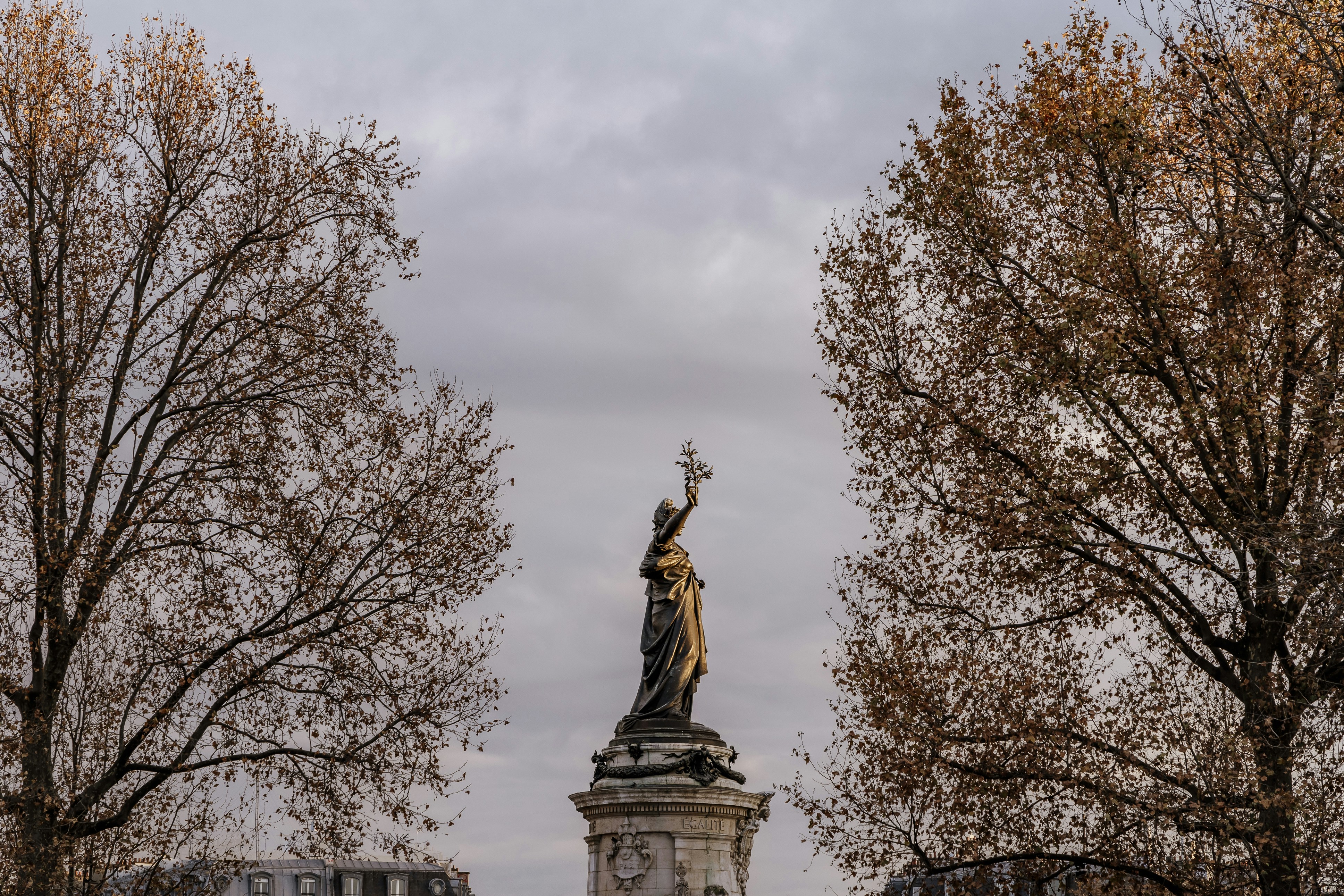 a statue of a woman holding a bird on top of a building