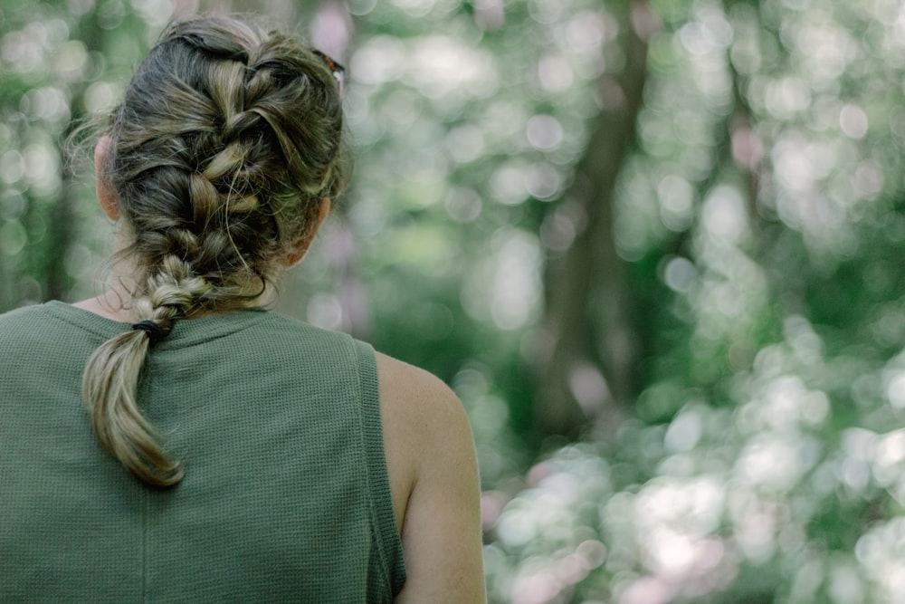 a woman with a braid in her hair walking through the woods