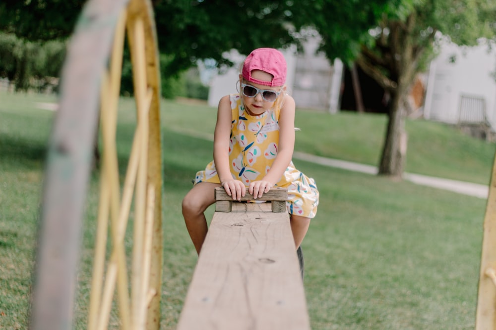 a little girl sitting on top of a wooden bench