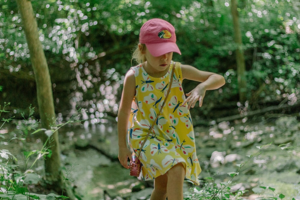 a little girl in a yellow dress and pink hat