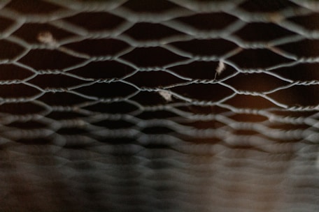 Close-up of woven wire netting being manufactured in a factory setting.