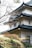 The image features a traditional Japanese-style building with multiple tiers and tiled, curved roofs. The architecture is set against a backdrop of leafless trees and a well-manicured garden with shrubs and grass. The scene conveys a sense of calm and traditional aesthetic.