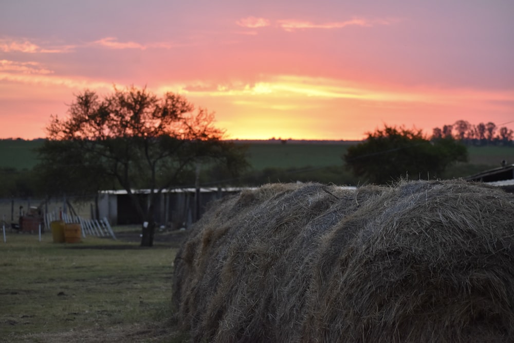 a large hay bale in a field with a sunset in the background
