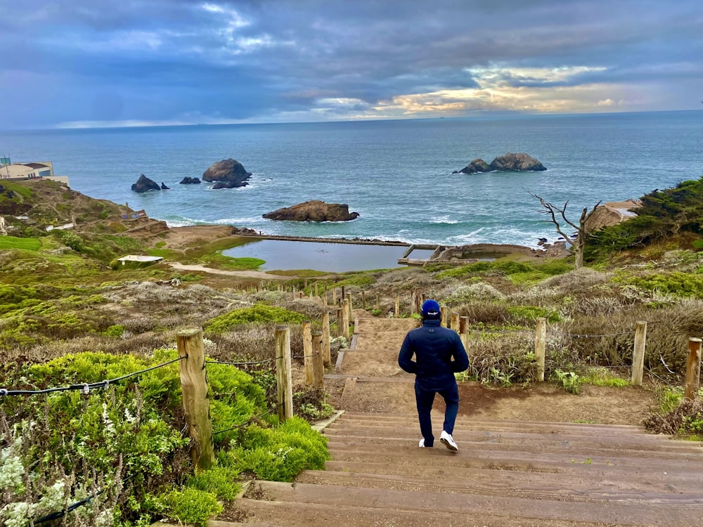 a man walking up a set of stairs towards the ocean