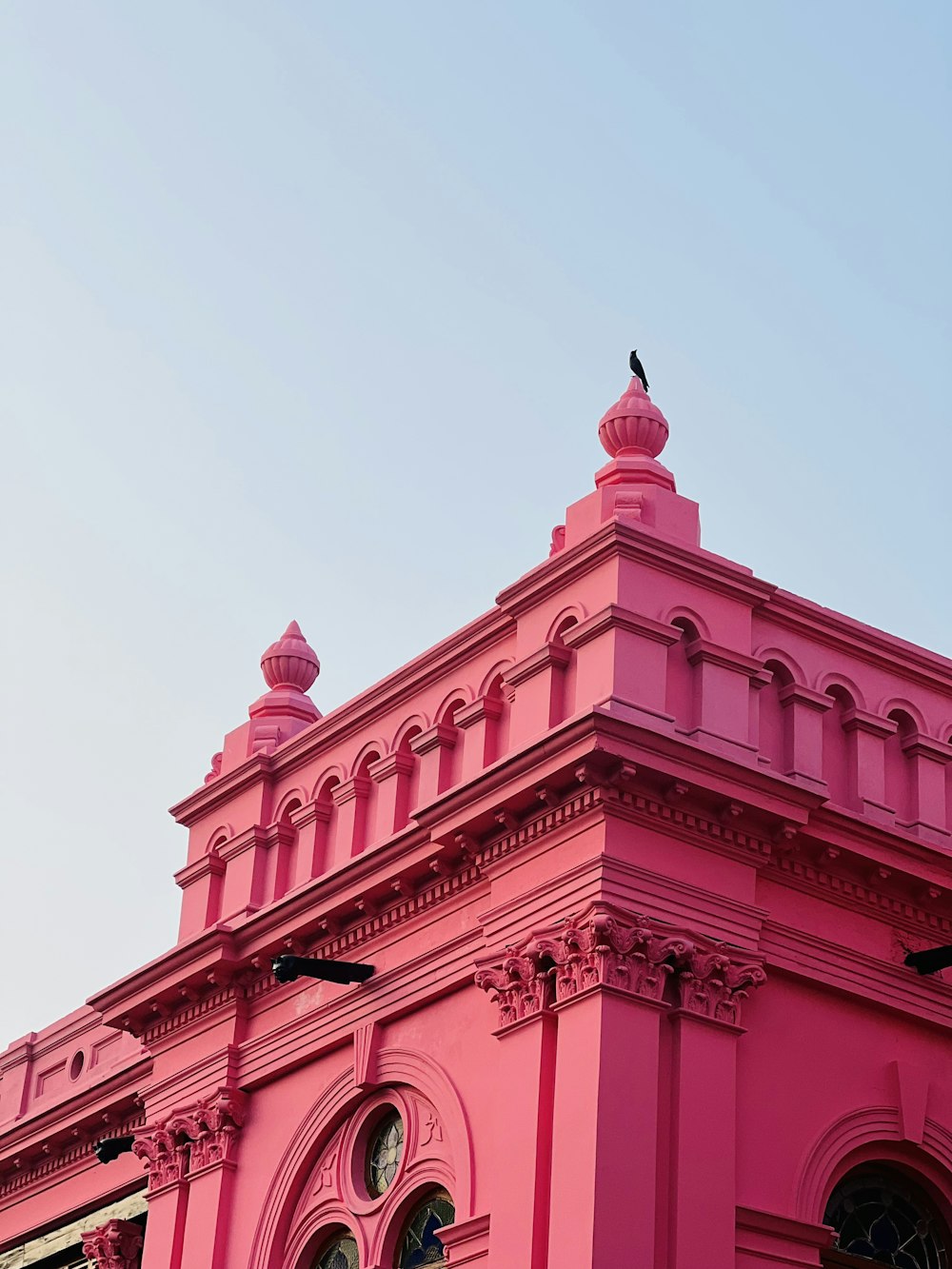 Un edificio rosa con un uccello seduto sopra di esso