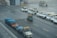 Several airport vehicles, including baggage carts covered with blue tarps, are lined up on the wet tarmac. Snow is falling, and a fleet of white service vehicles with yellow details is parked nearby.
