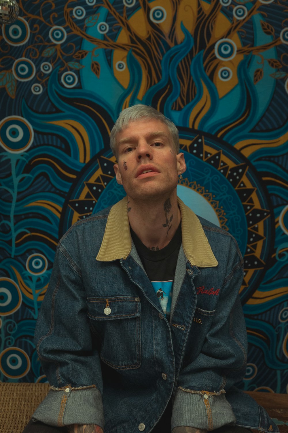 a man sitting in front of a colorful wall