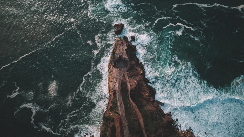 an aerial view of the ocean with waves crashing on the rocks