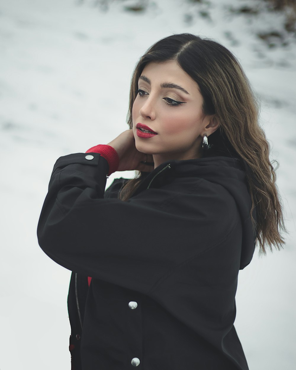 a woman standing in the snow wearing a black jacket