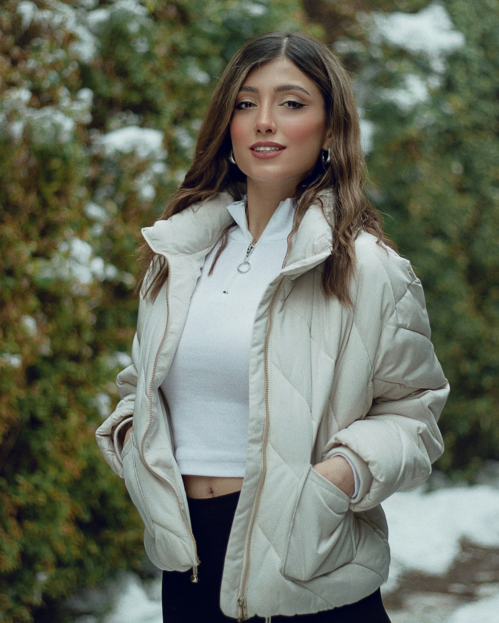 a woman standing in the snow wearing a jacket