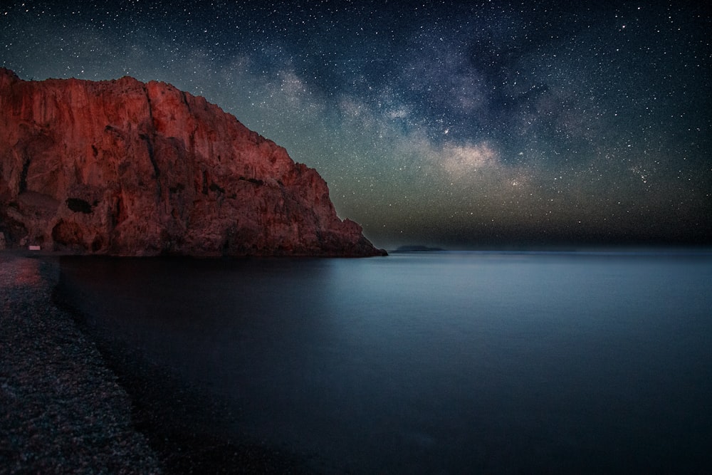 the night sky over the ocean with stars above it