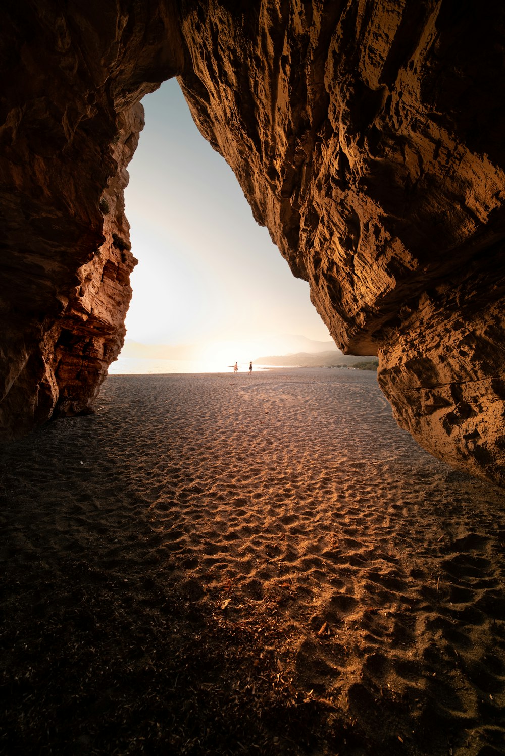 a person standing in a cave on a beach