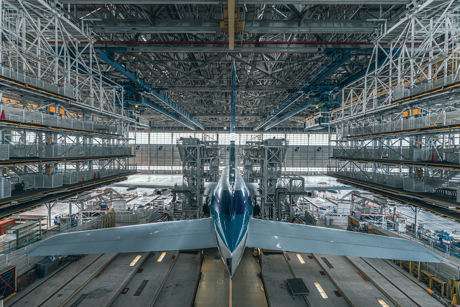 A jet on the line in an aircraft assembly hall, framed by work platforms