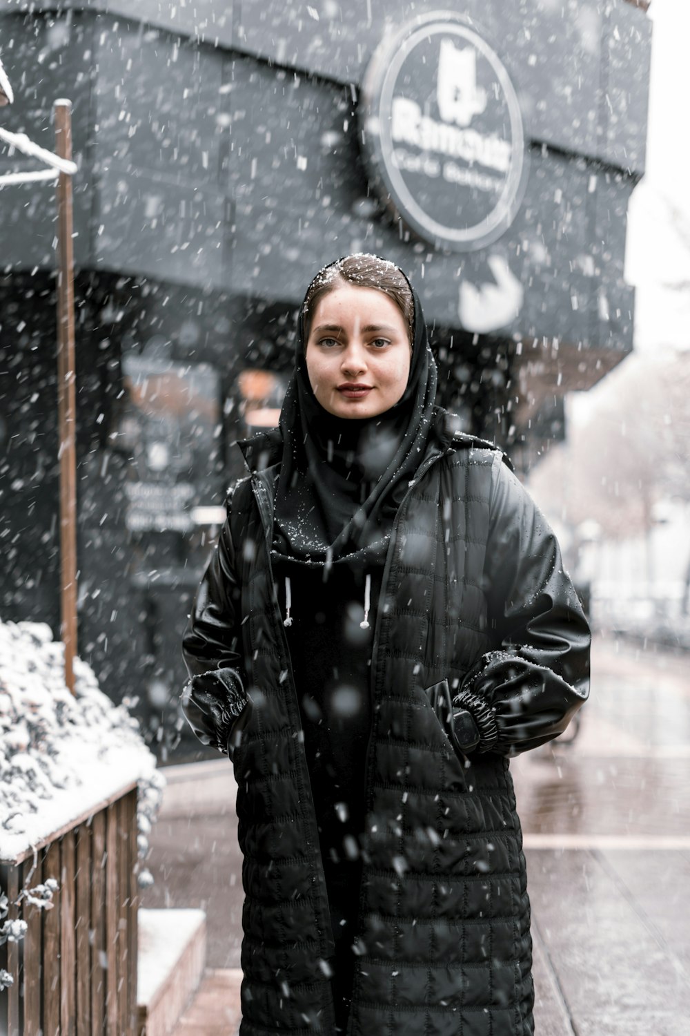 a woman standing on a sidewalk in the snow