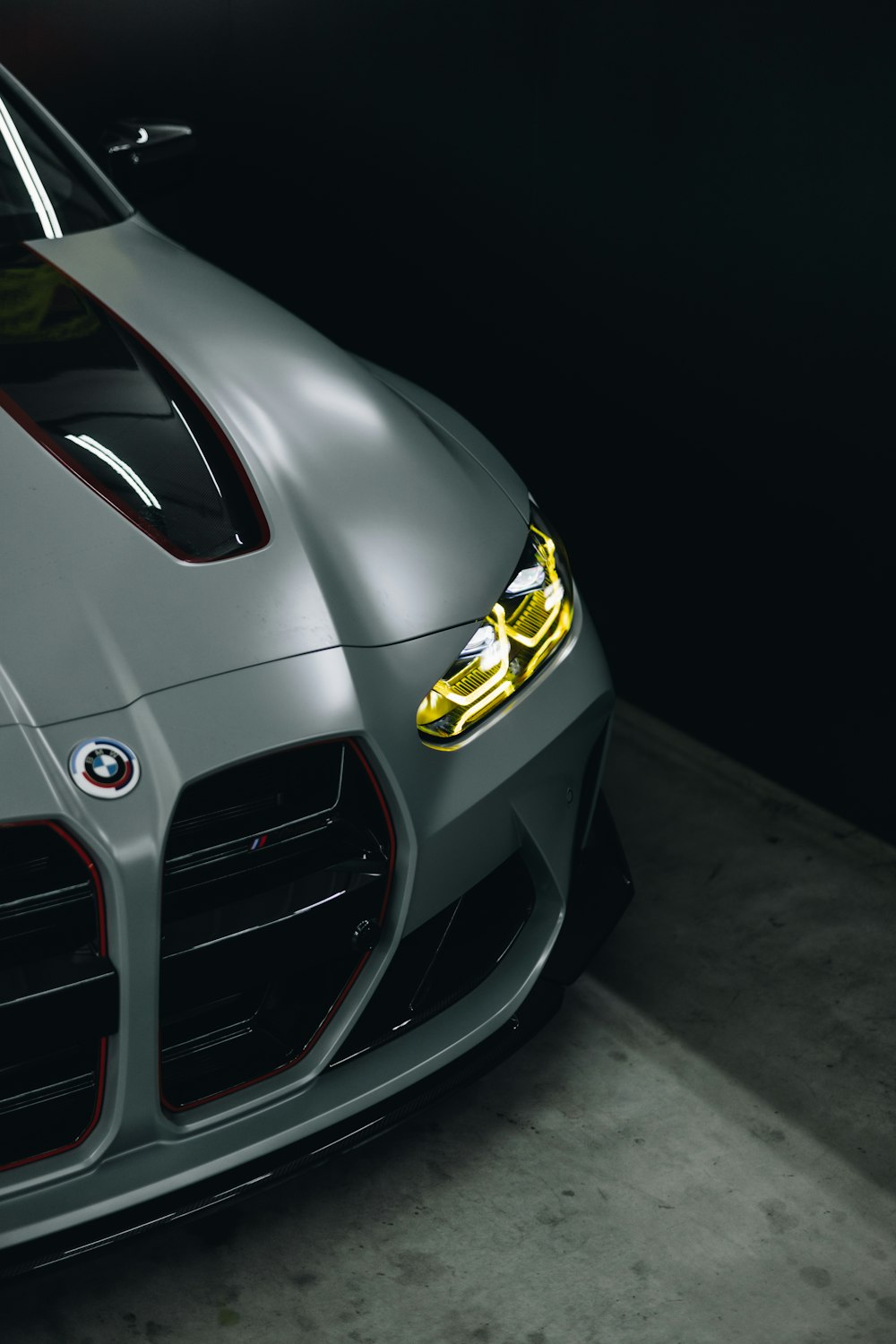 the front of a gray sports car in a dark room