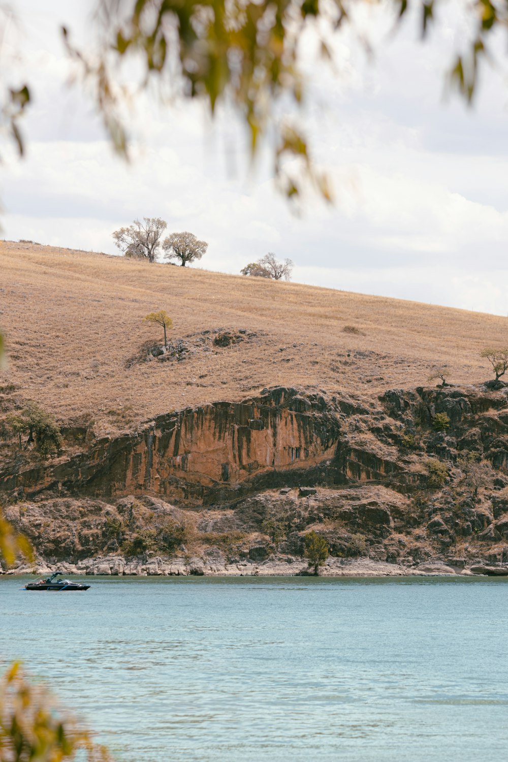 a boat is on the water near a hill