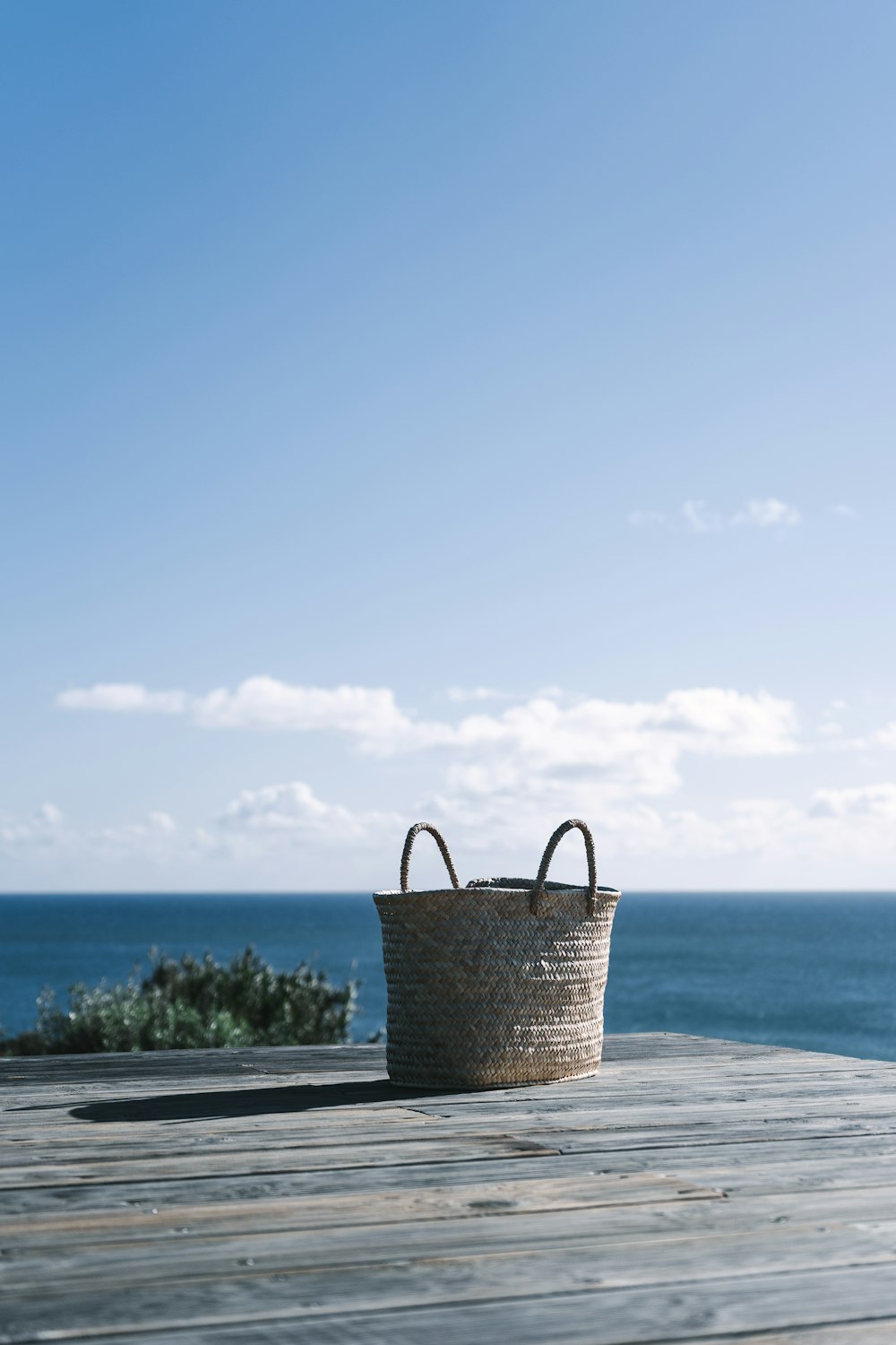 a basket sitting on top of a wooden table next to the ocean