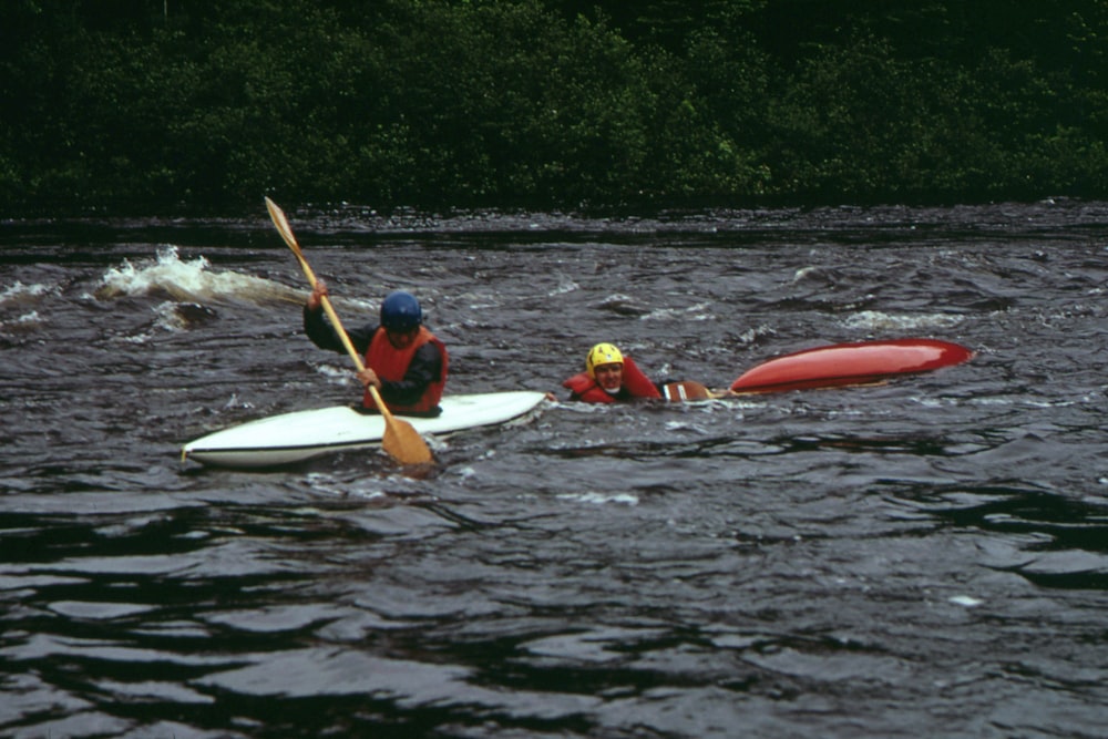 two people in kayaks paddling down a river