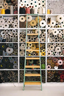 A warm corner with spools of thread and crochet hooks arranged neatly on wooden shelves.