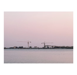 Sunset view of a reclaimed land area with ongoing civil construction by the water.