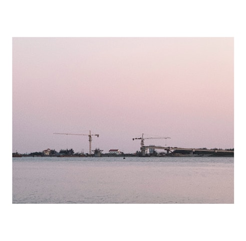 A team of engineers reviewing blueprints on a waterfront construction site during golden hour.