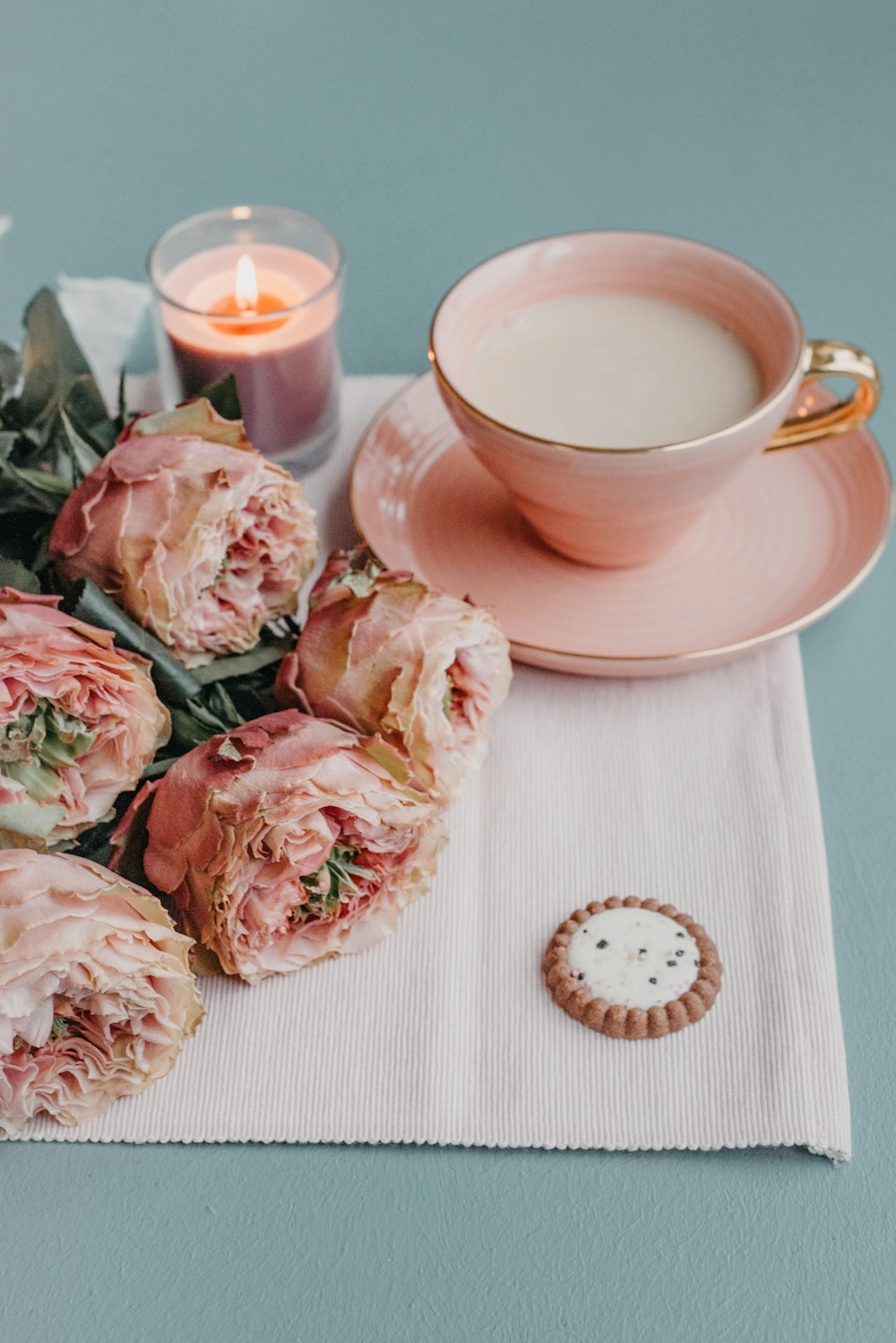 a table topped with pink flowers next to a cup of coffee