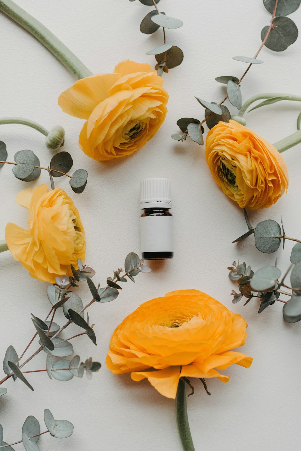 a bottle of essential oils surrounded by flowers