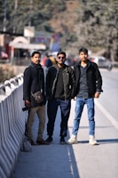 three men standing next to each other on a bridge