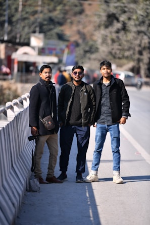 three men standing next to each other on a bridge