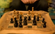 A close-up of hands setting up a chessboard with classic wooden pieces in a bright classroom.
