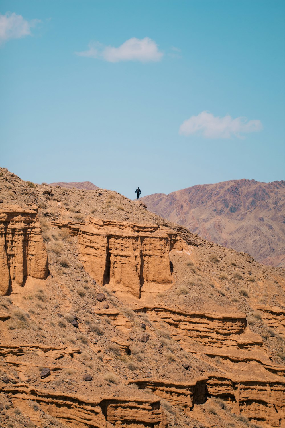 una persona in piedi sulla cima di una collina rocciosa