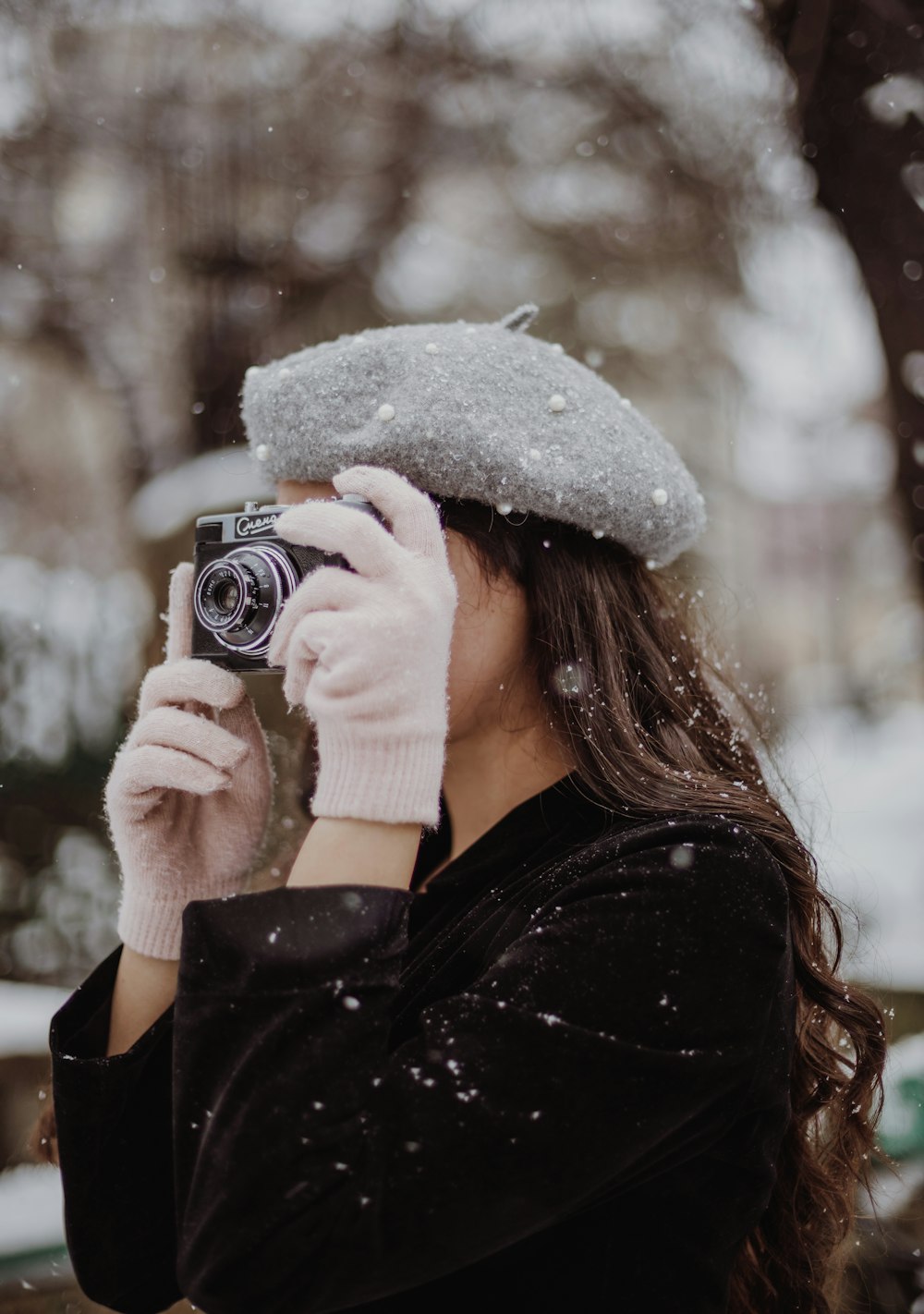雪の中でカメラで写真を撮る女性