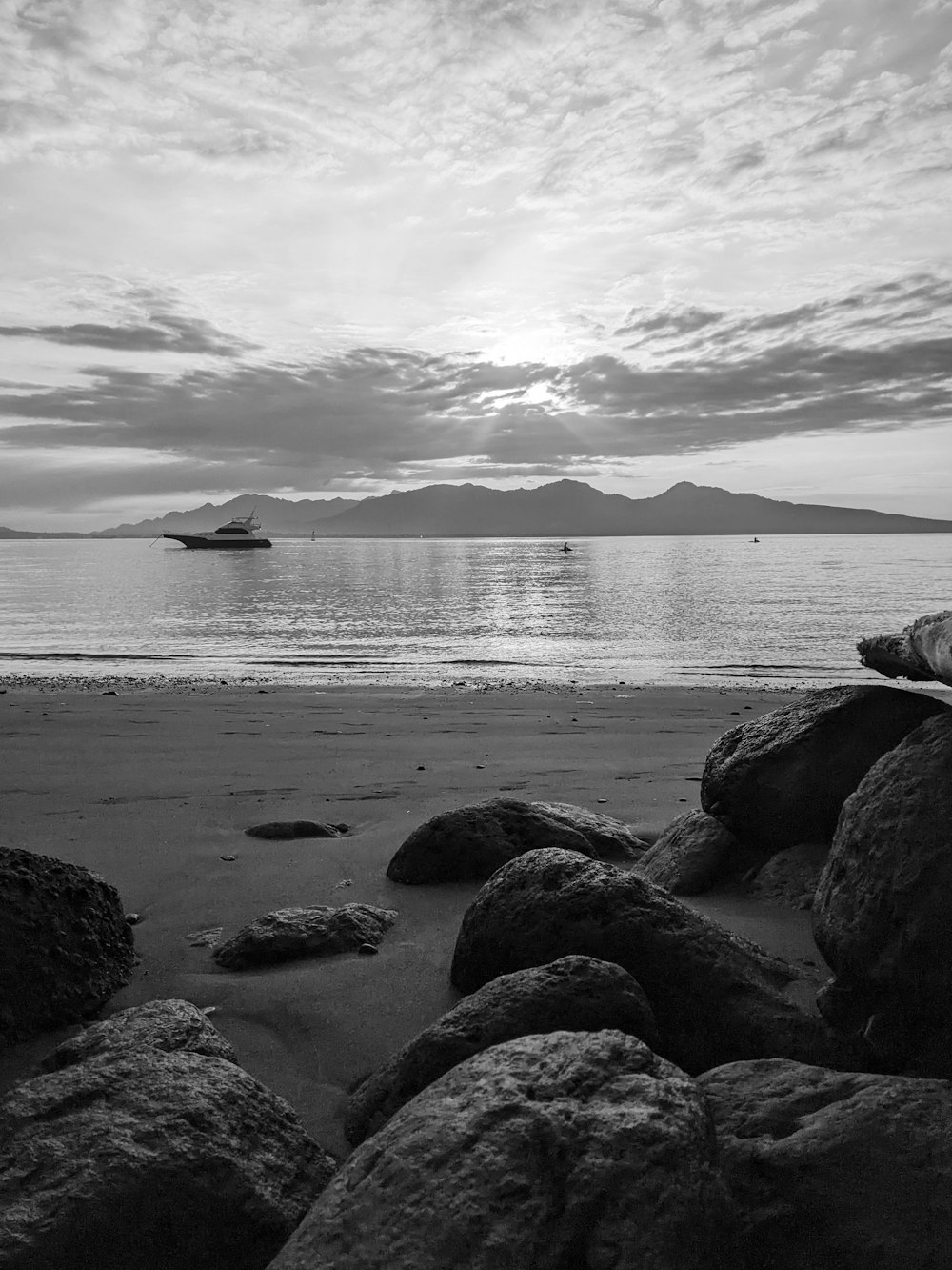 a black and white photo of a beach with rocks