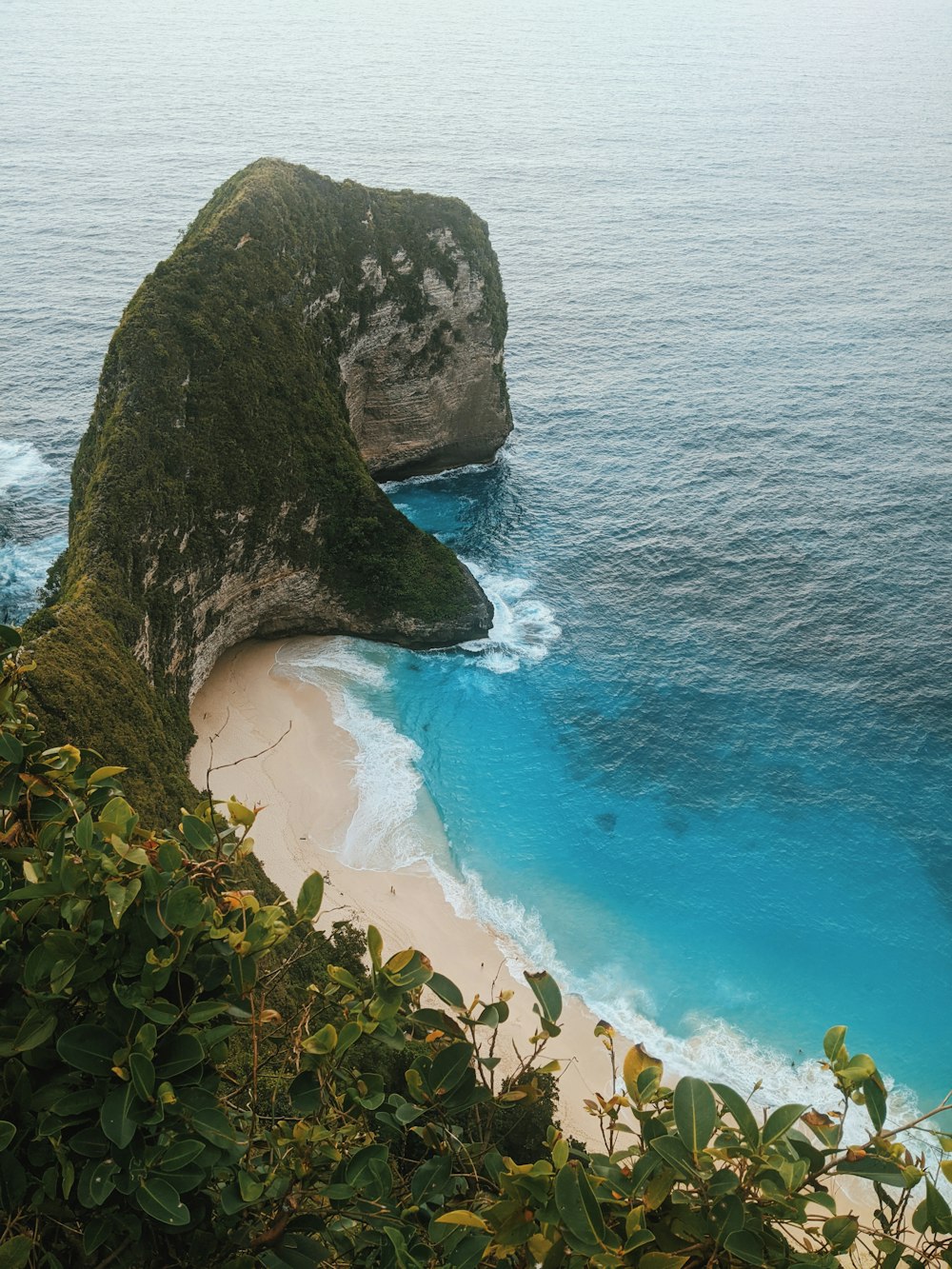 a beach with a large rock sticking out of the water