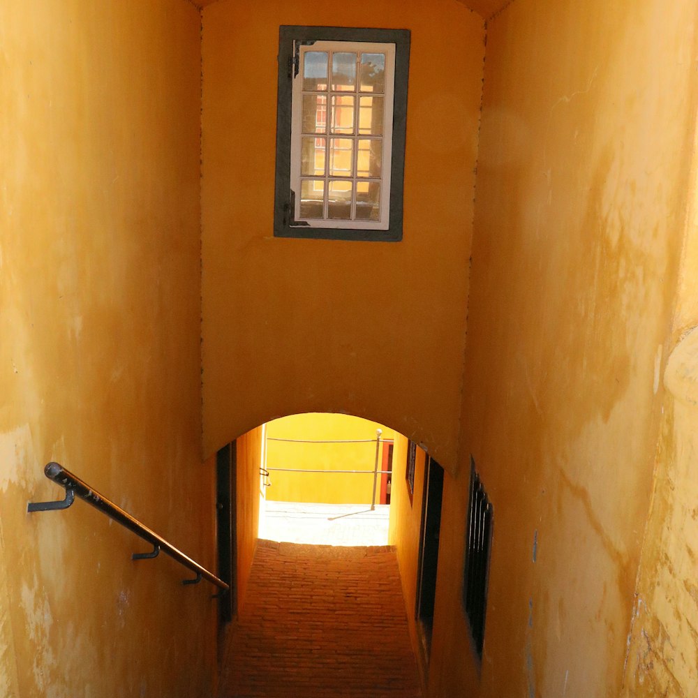 a narrow hallway with a window and railing