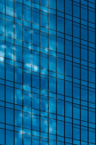 Close-up of a glass building facade reflecting a deep navy sky with subtle gold highlights.