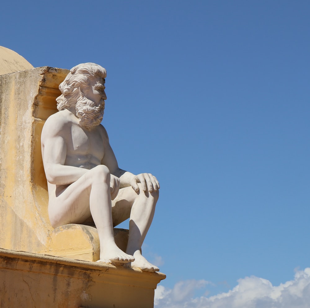 a statue of a man sitting on top of a building