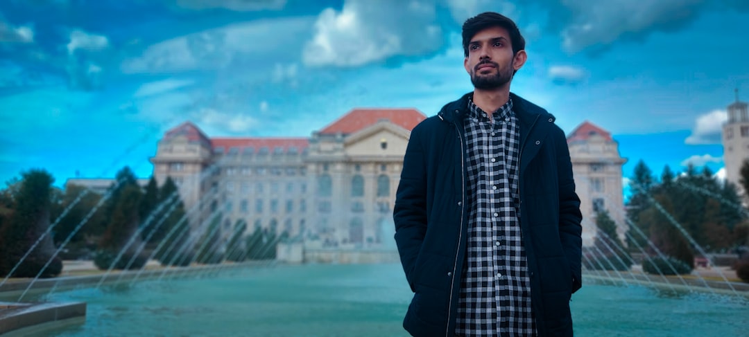 a man standing in front of a fountain, Boy in front of University of Debrecen