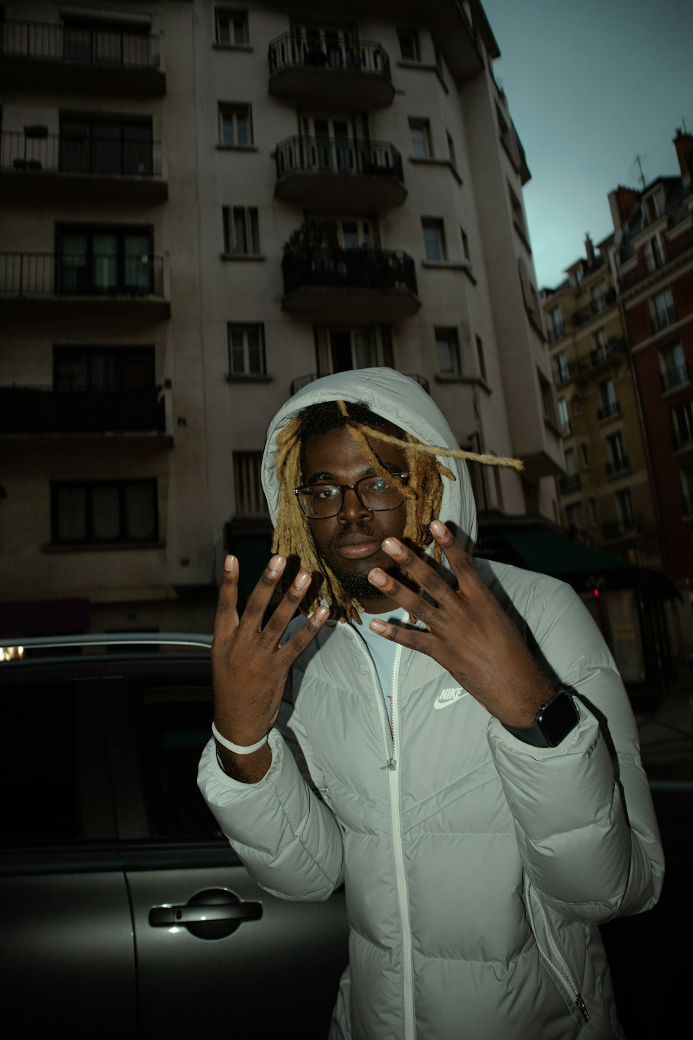 a man standing in front of a car holding a cigarette