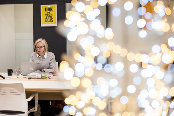 A professional woman working thoughtfully at her desk with marketing materials and a laptop, symbolizing strategic creativity.