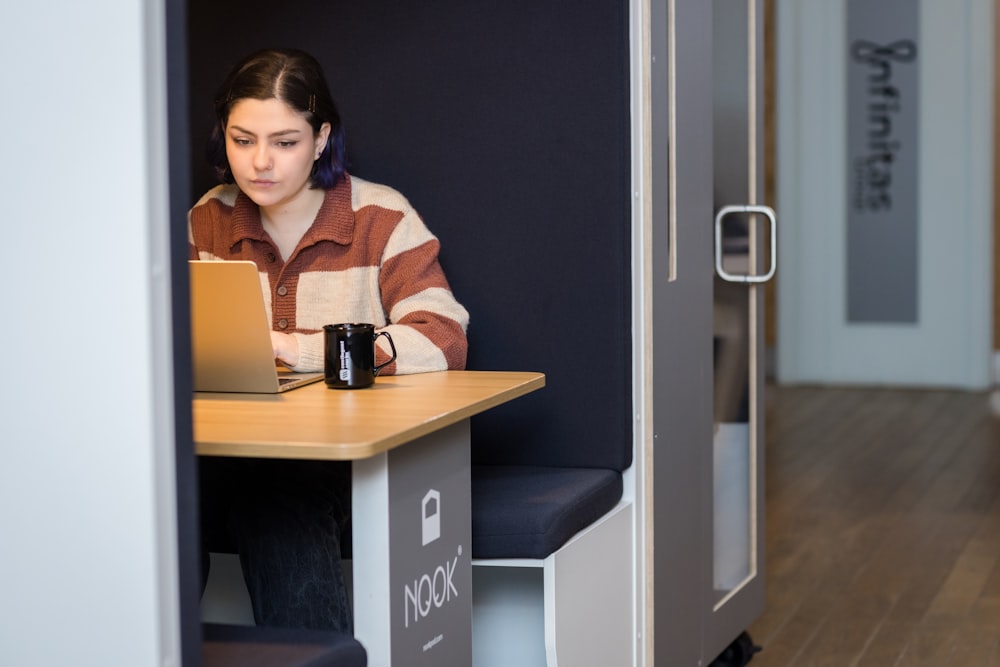 a woman sitting at a table with a laptop