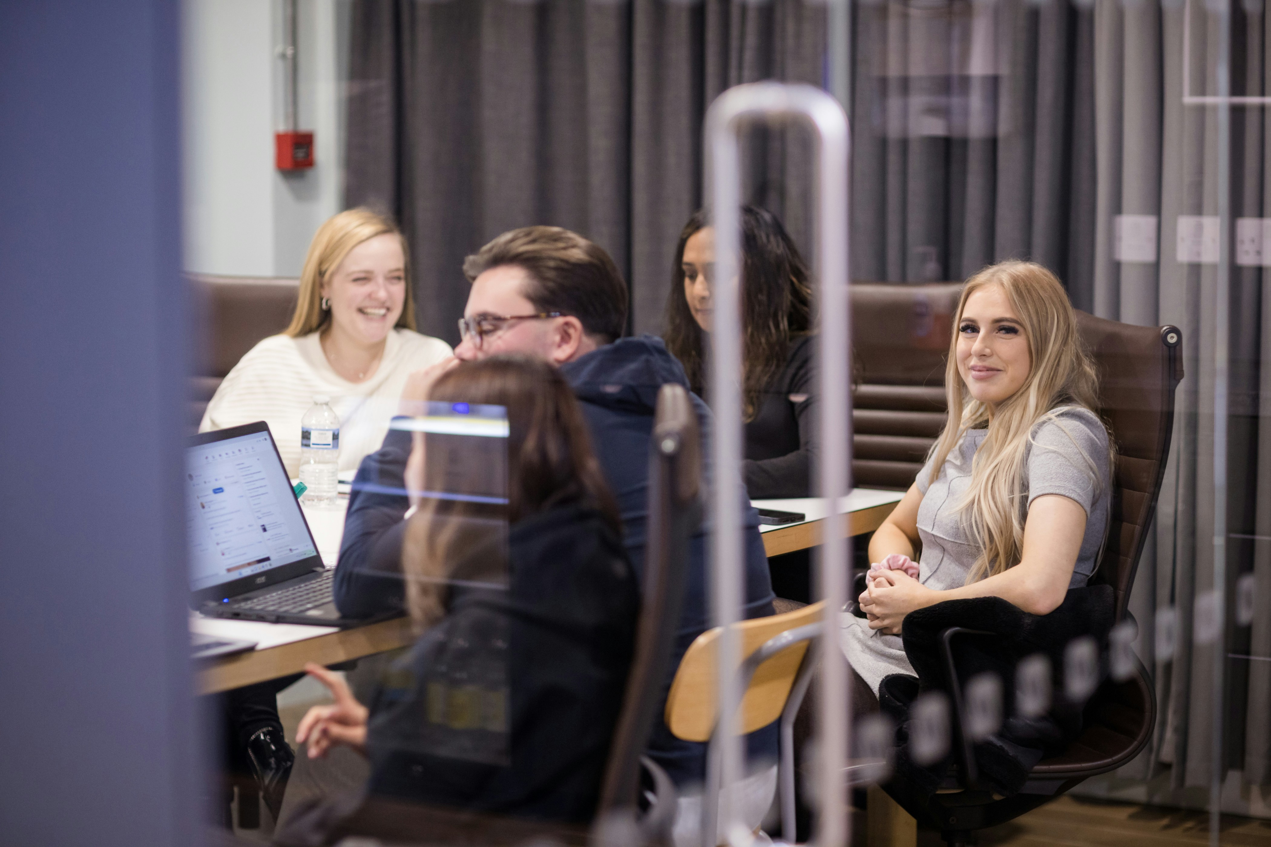 Un grupo de personas sentadas alrededor de una mesa con computadoras portátiles