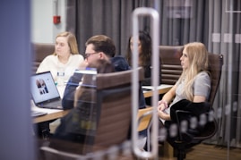 a group of people sitting at a table with laptops