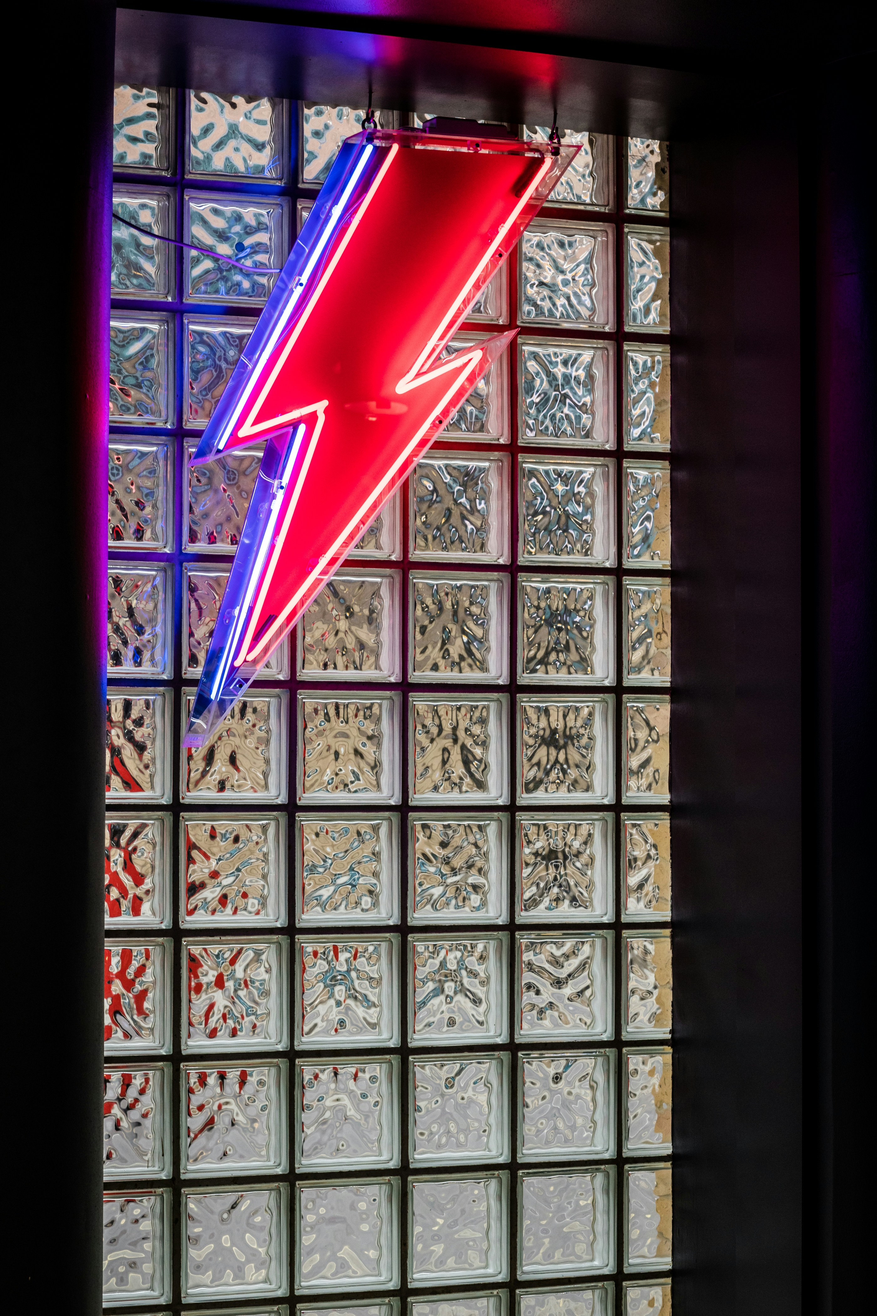 Un letrero de neón rojo colgando del costado de una ventana