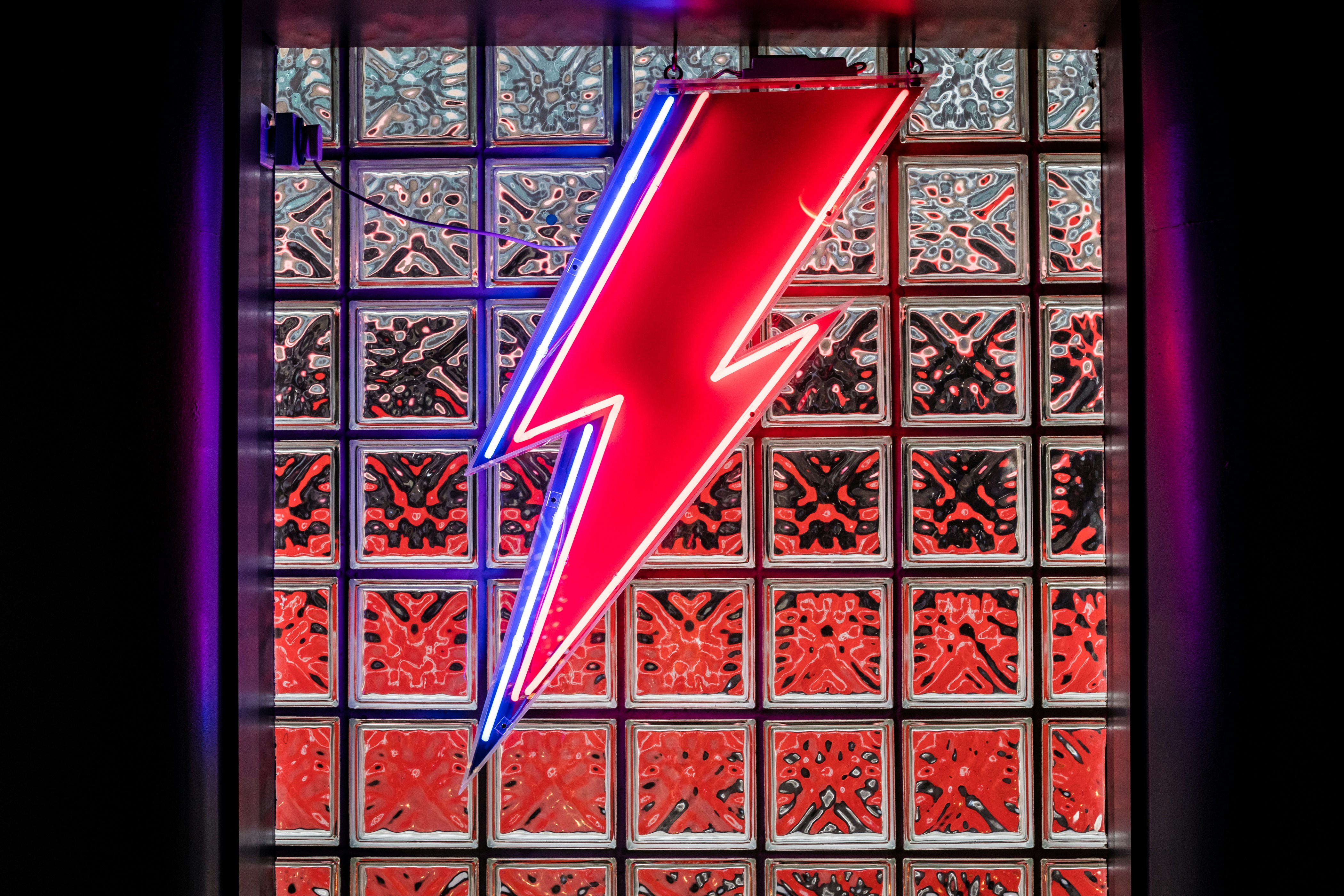 Un letrero de neón rojo y azul frente a una ventana