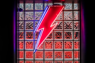 A bright yellow electric bolt overlay on a blue-toned photo of an electrician installing wiring.